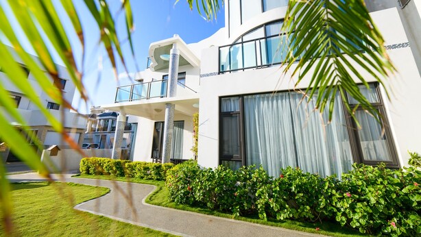 A modern hotel with a curved driveway, lush greenery, and large windows. - Peng Hu 616 B&B (Magong)