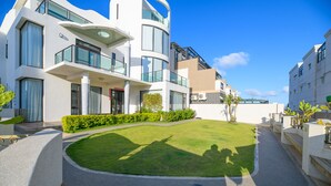 A modern residential building with a curved facade, large windows, and a well-maintained lawn. - Peng Hu 616 B&B (Magong)