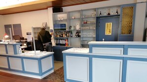 Zona de bar con decoración azul y blanca, estantes con botellas y vasos, y una barra con un menú.