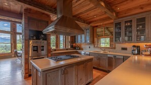 A spacious kitchen with wooden cabinets, a large island, stainless steel appliances, and large windows offering a view of the mountains. - Sleeps 23, 8 BR w/ full bath, majestic views on 35 acres, walk to town (Crested Butte)