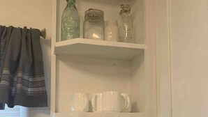 A kitchen with white cabinets, a tiled backsplash, and shelves holding white mugs and glass jars. - 3 BR Walking Distance to ATT, Globe Life & Entertainment District (Arlington)