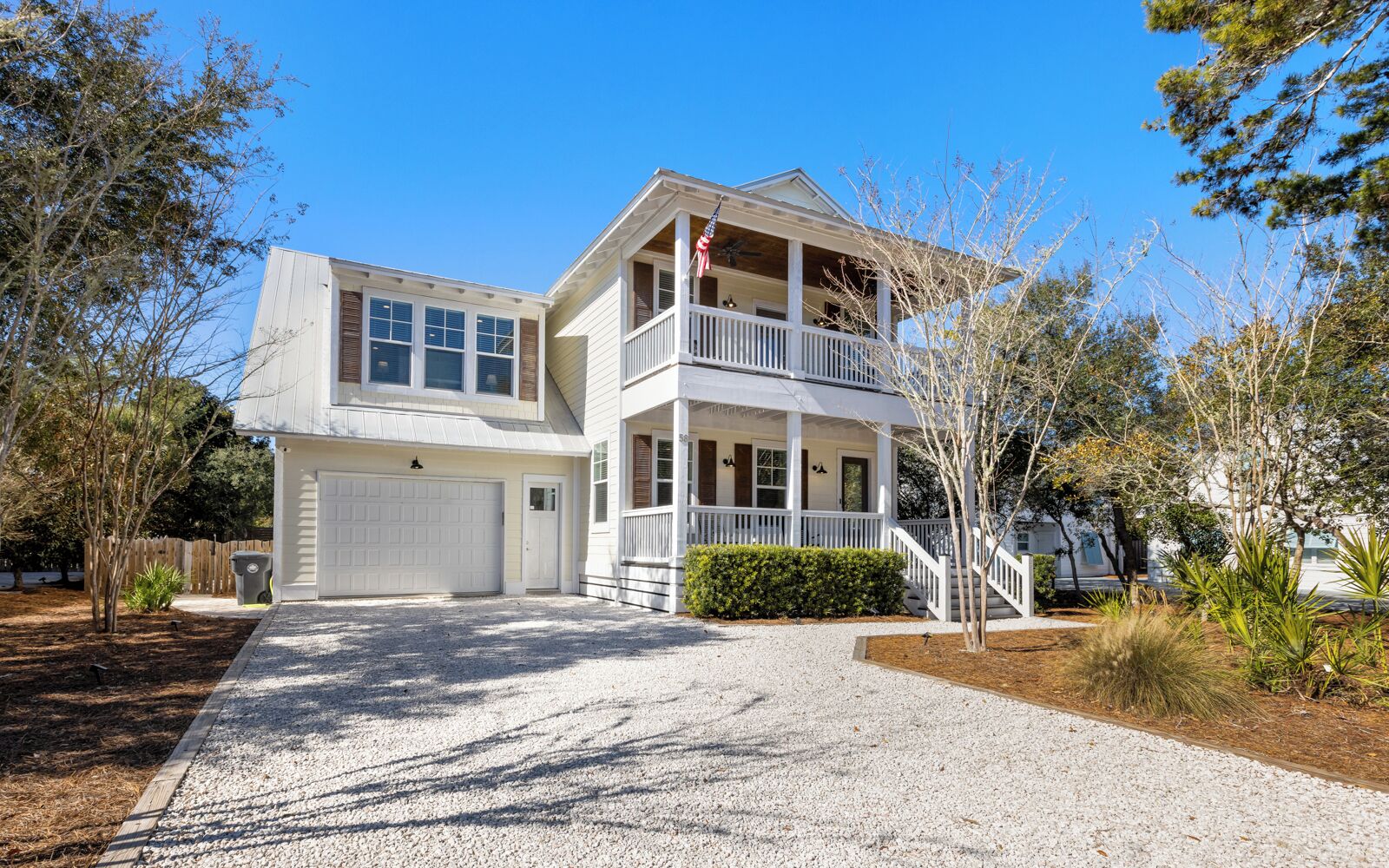 A two-story house with a front porch, a garage, and a flag.