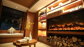 Ein modernes Interieur mit einem Bücherregal aus Holz, einem Kamin und einer Sitzecke mit Kissen und einer Vase.