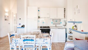 Eine kleine Küche mit weißen Schränken, einem Esstisch mit Stühlen und einem kleinen Kühlschrank.