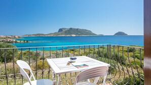 Ein Balkon mit Tisch und Stühlen mit Blick auf die Küste.