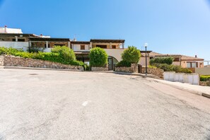 A residential street with houses, a paved road, and a stone wall.