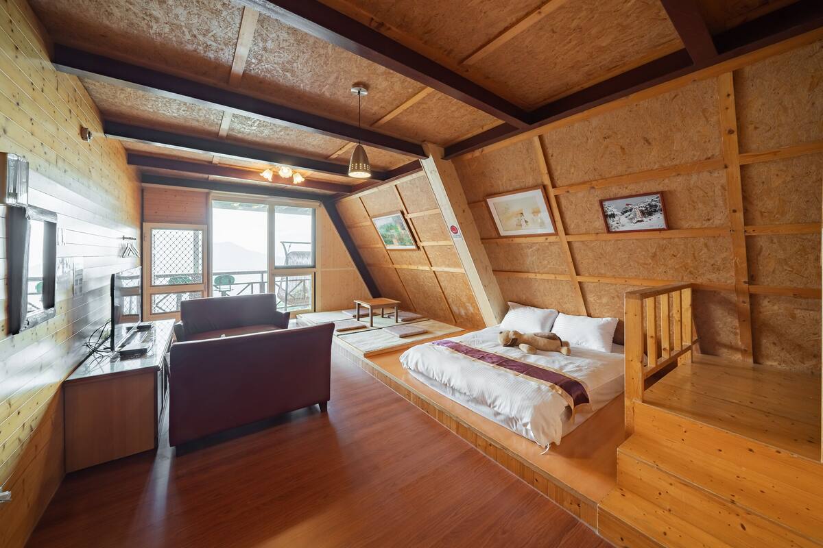A cozy, wooden cabin-style room with a loft bed, a desk, and a chair.