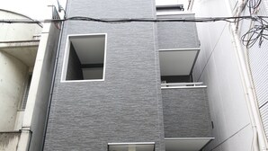 En modern byggnad i två våningar med en grå fasad, en liten balkong på övre våningen och en tydligt markerad entré.