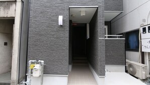 En modern byggnad med en smal entré, ett synligt vattenrör och en luftkonditioneringsenhet.