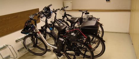 Une pièce où des vélos sont appuyés contre un mur, avec un panneau en bois et un plafond blanc.