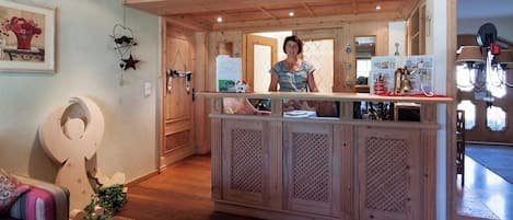 Un espace d’accueil avec un comptoir en bois, un élément décoratif mural et une porte visible donnant sur une autre pièce.
