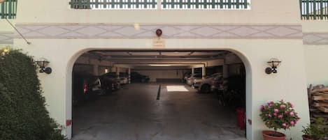 Un aparcamiento cubierto con varios coches estacionados en su interior.
