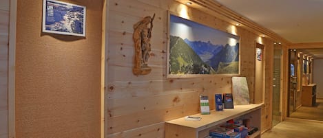 Un intérieur en bois agrémenté d’une carte encadrée, d’une statue et d’un grand tableau représentant un paysage de montagne.