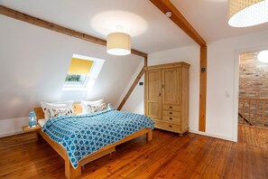 Un dormitorio con una cama de madera, un tragaluz, un armario y una pared de ladrillo.