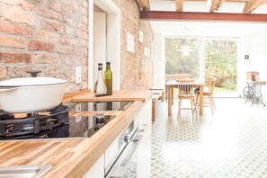 Una cocina con pared de ladrillo, encimera de madera y zona de comedor con mesa y sillas.