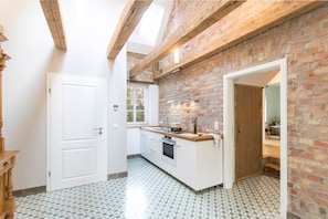 Una cocina con pared de ladrillo, una puerta blanca y una ventana.