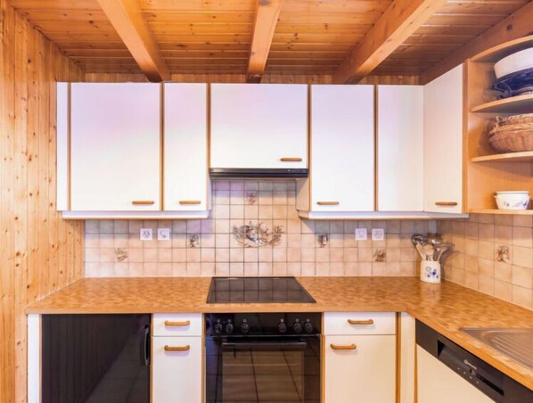 A kitchen with wooden cabinets, a tiled backsplash, and a stove.