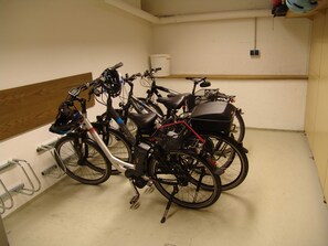 Une pièce où des vélos sont appuyés contre un mur, avec un panneau en bois et un plafond blanc.