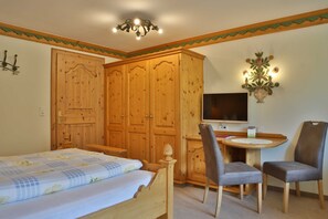 Une chambre à coucher comprenant un lit, un bureau avec une chaise, une télévision et une armoire.