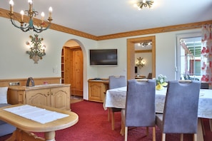 Ein Essbereich mit Tisch, Stühlen, einem Fernseher und einem Holzschrank.