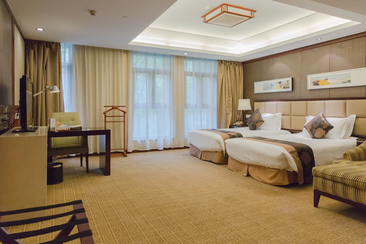 Een hotelkamer met twee bedden, een bureau, een stoel en een televisie.