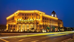 A large, illuminated building with a prominent clock tower, likely a hotel, featuring a grand entrance and multiple floors. - Nanjing Greenland Yuhao Hot Spring Hotel (Nanjing)