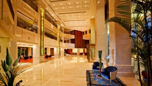 A spacious lobby with a polished marble floor, a blue sofa, and a large potted plant. - Nanjing Greenland Yuhao Hot Spring Hotel (Nanjing)