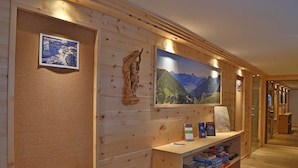 Un intérieur en bois agrémenté d’une carte encadrée, d’une statue et d’un grand tableau représentant un paysage de montagne.