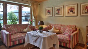 Une pièce chaleureuse avec deux canapés à rayures, une table sur laquelle est posé un vase, et des œuvres d’art florales encadrées accrochées au mur.