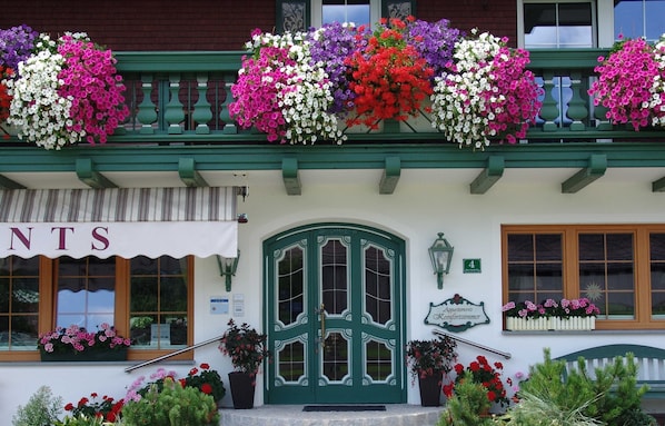 A building with a green door, flower boxes, and a sign that says 'Apartments Komfortzimmer'.