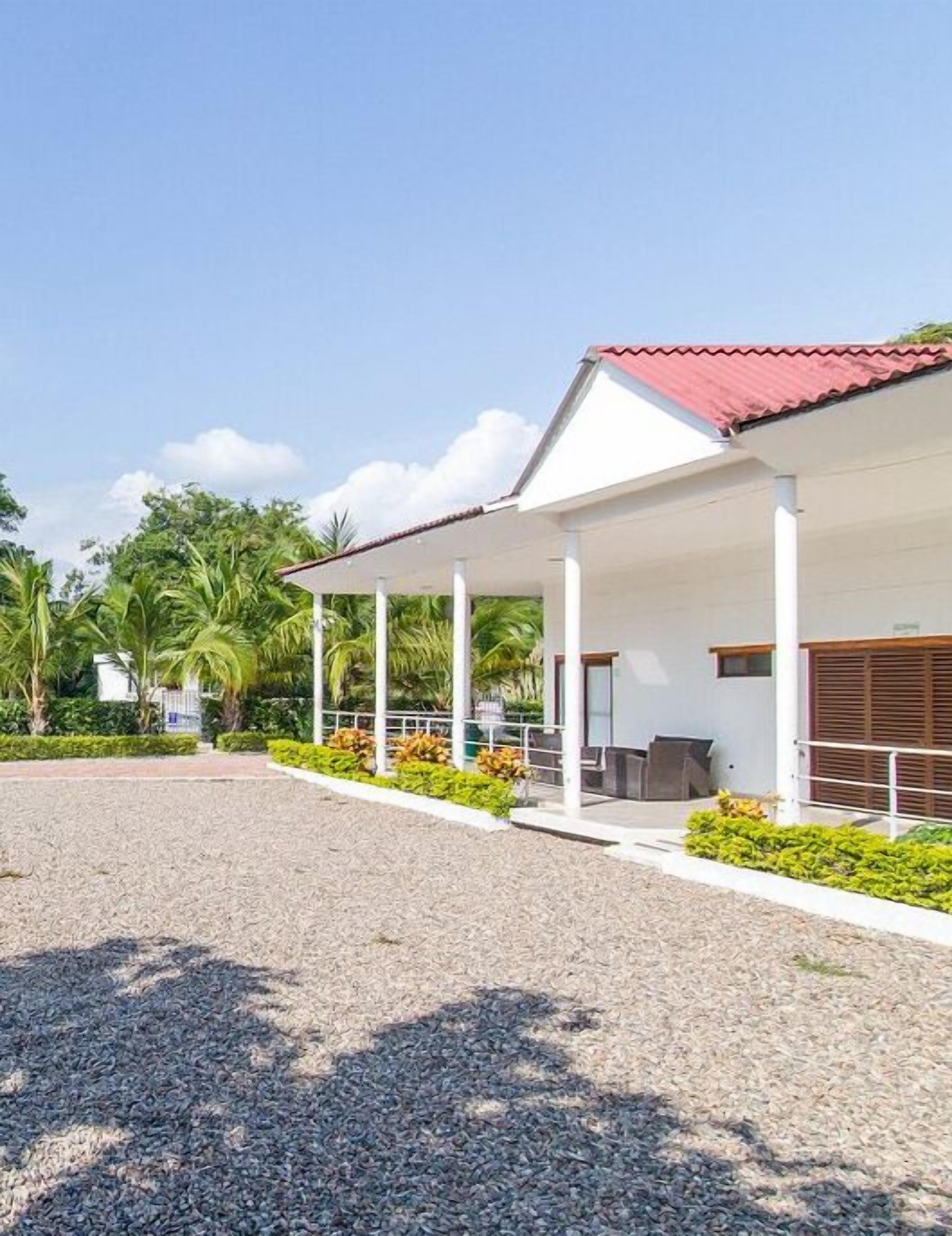 A covered outdoor area with a gravel path leading to a building with a red roof.