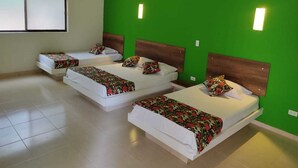 A hotel room with three beds, each with a wooden headboard and floral bedding. - Arizona Ranch Hotel (Girardot)