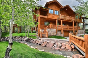A log cabin with a stone foundation, wooden balconies, and a stone retaining wall.