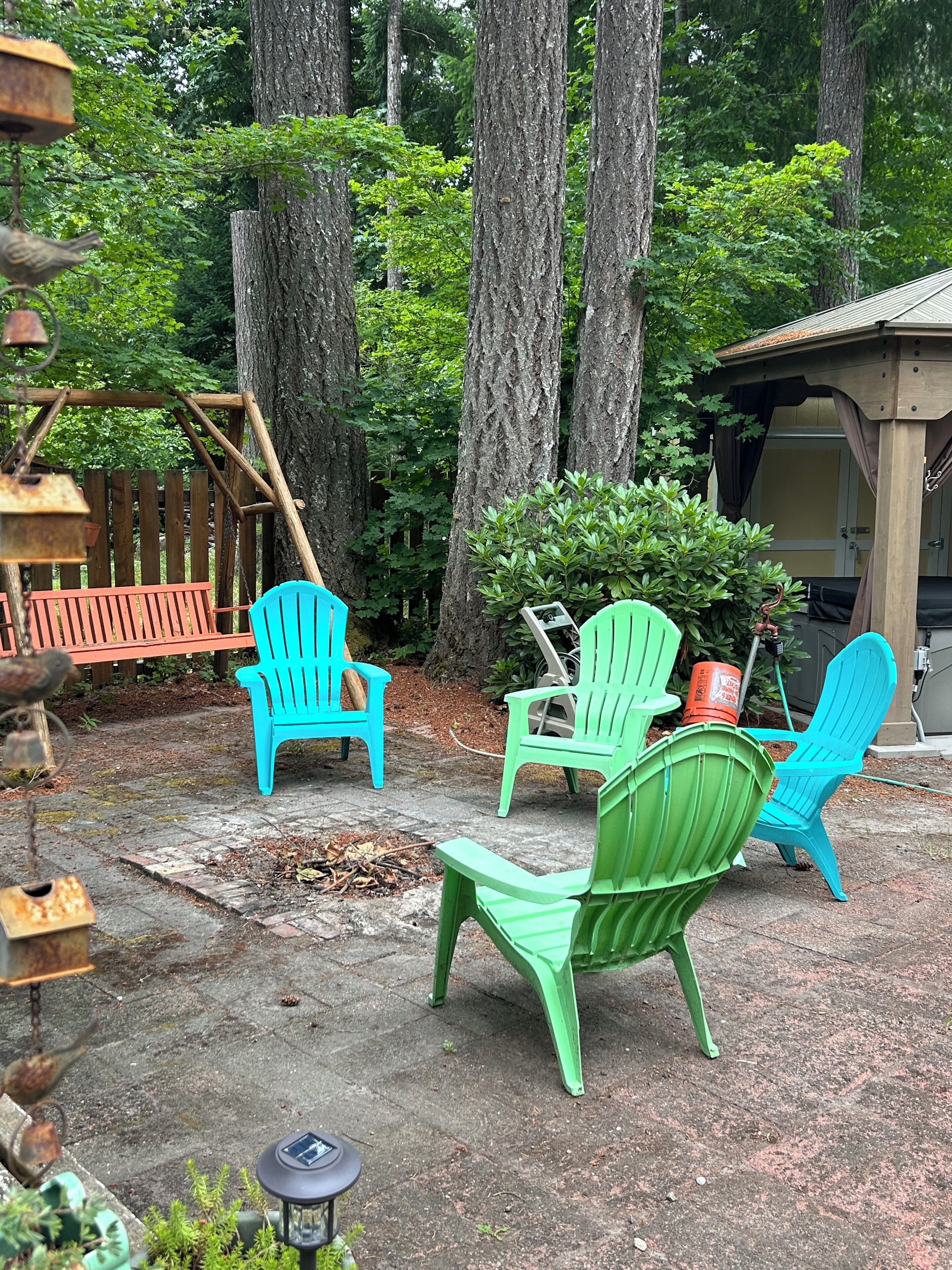 A backyard with Adirondack chairs, a wooden deck, and a shed.