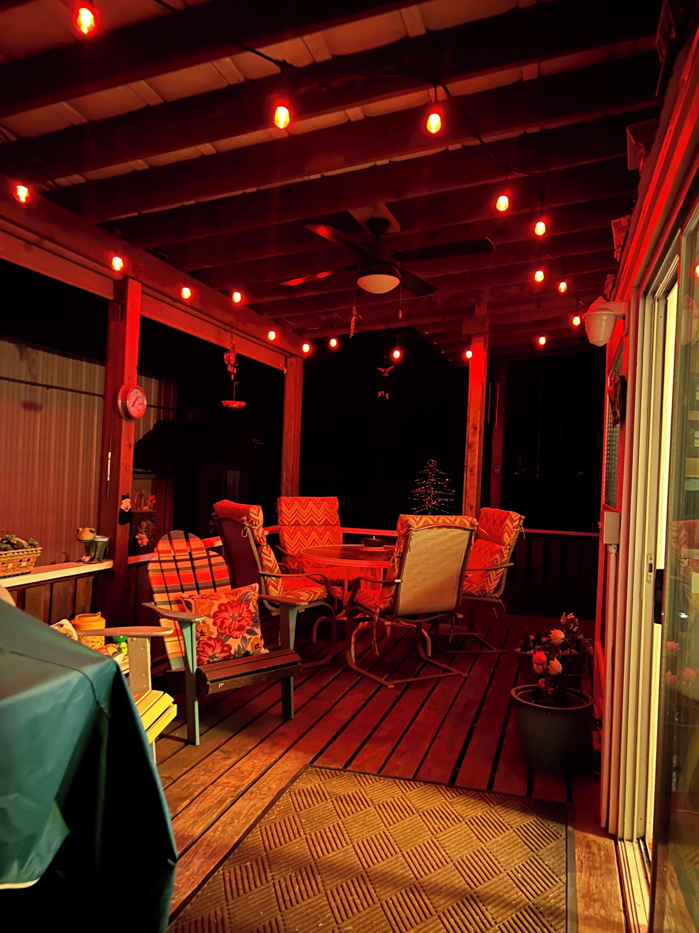 Un patio al aire libre con suelo de madera, ventilador de techo y luces colgantes.