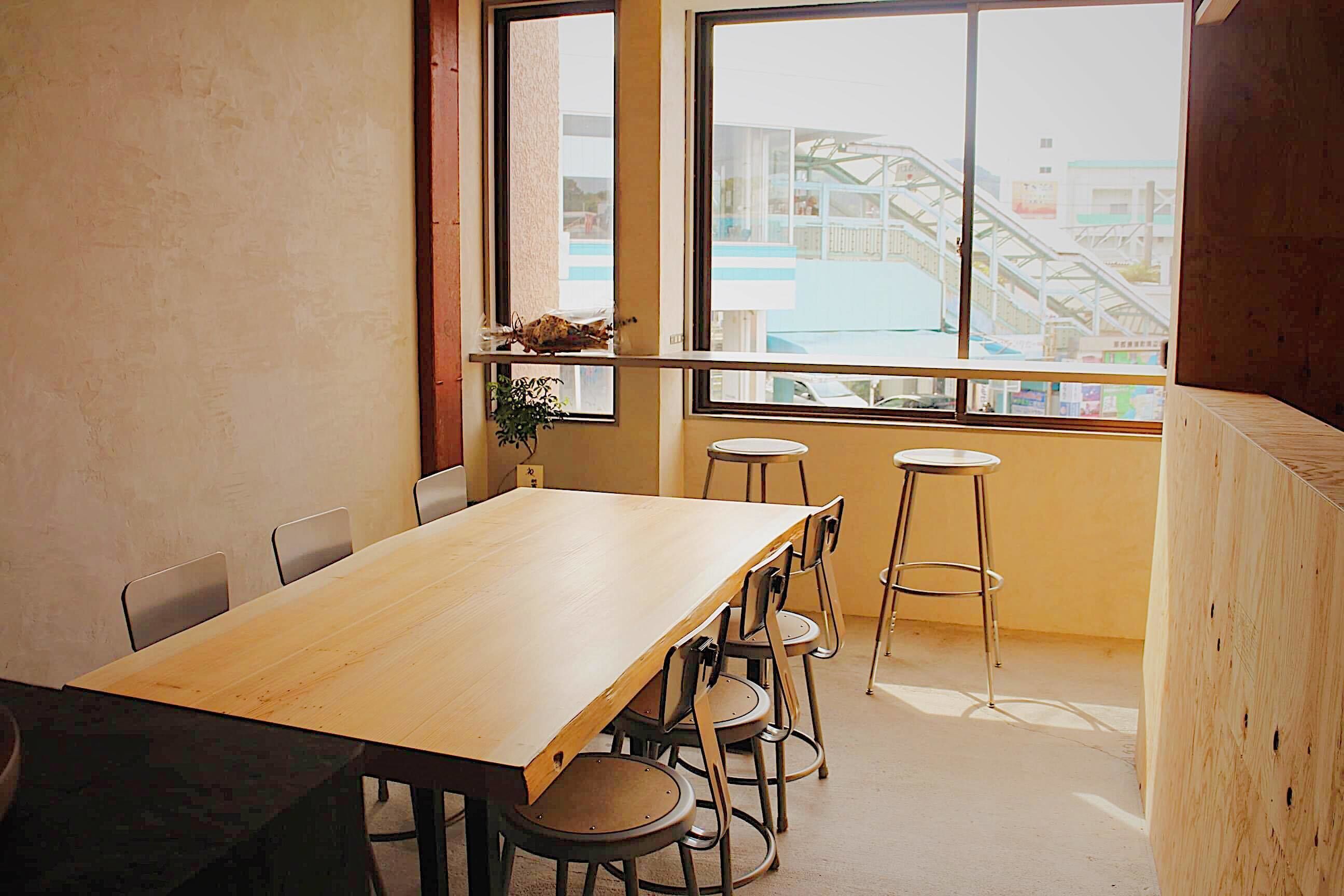A room with a large wooden table, four chairs, and a window with a view of a building.