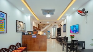 A hotel reception area with a reception desk, seating, a staircase, and a TV screen. - Vip House Hoi An (Da Nang)