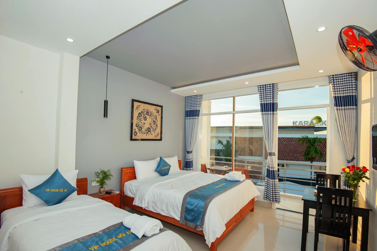 A hotel room with two beds, a balcony with a view, and a dining area.