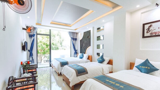 A hotel room with three beds, a large window, and a fan. - Vip House Hoi An (Da Nang)