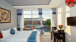 A hotel room with a bed, a dining table with chairs, a TV, and a balcony with curtains. - Vip House Hoi An (Da Nang)