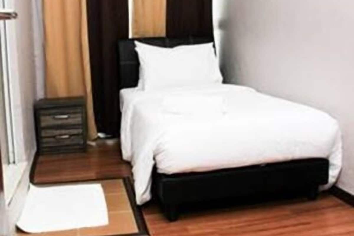 A bedroom with a bed, a bedside table, a nightstand, and a window with curtains.