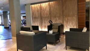 A lobby with wicker furniture, a wooden partition, and a tiled floor. - Lake front condo at the Island (Lago Vista)