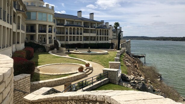 A large, multi-story building with a dome and multiple balconies overlooking a body of water. - Lake front condo at the Island (Lago Vista)