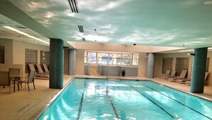 An indoor swimming pool with clear water, tiled walls, and lounge chairs around the perimeter. - Lake front condo at the Island (Lago Vista)