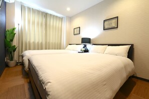A large bed with white linens, a bedside table with a lamp, and a potted plant. - Elizabeth Garden Kuromon (Osaka)