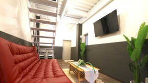 A modern living room with a red sofa, a wooden coffee table, and a large potted plant. - Elizabeth Garden Kuromon (Osaka)