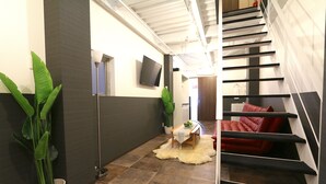A modern interior with a staircase, a flat-screen TV, and a potted plant. - Elizabeth Garden Kuromon (Osaka)