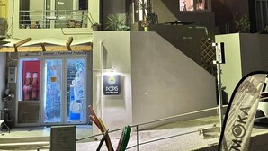 En moderne bygning med to etager, en balkon og en butik i stueplan.