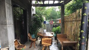 Un espace extérieur abrité, doté d’un sol recouvert de mosaïques, de mobilier en bois et de plantes en pot.