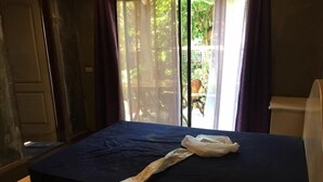 Une chambre avec un lit, une fenêtre avec des rideaux et une vue sur la verdure.